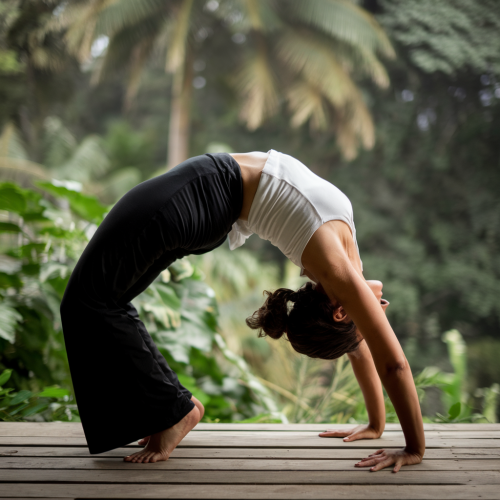 A young woman performing a yoga pose in a peaceful garden surrounded by lush greenery.